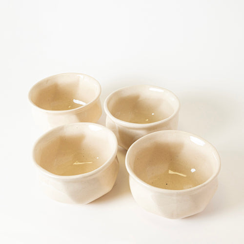 Four off-white RAITA SIP BOWLs by kalakriti, each with a glossy ceramic finish and subtle shape variations, are arranged together on a white background, highlighting their simple handmade look.